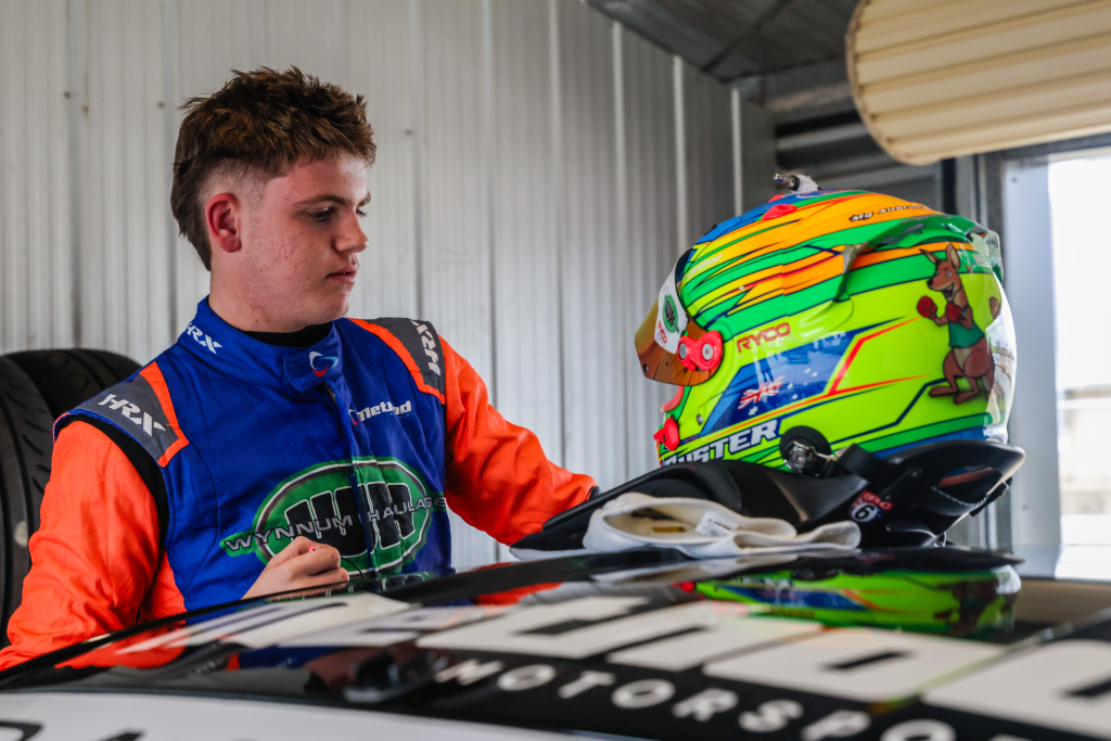 Buster Bailey preparing beside his racing kart and helmet.